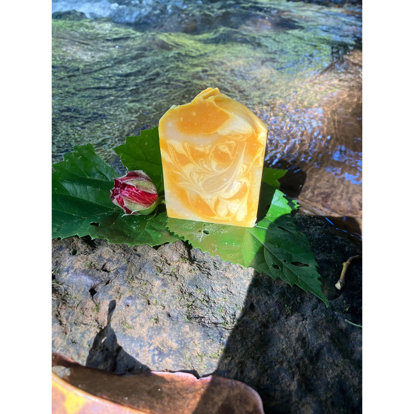 Yellow soap bar on green leaves with a natural background