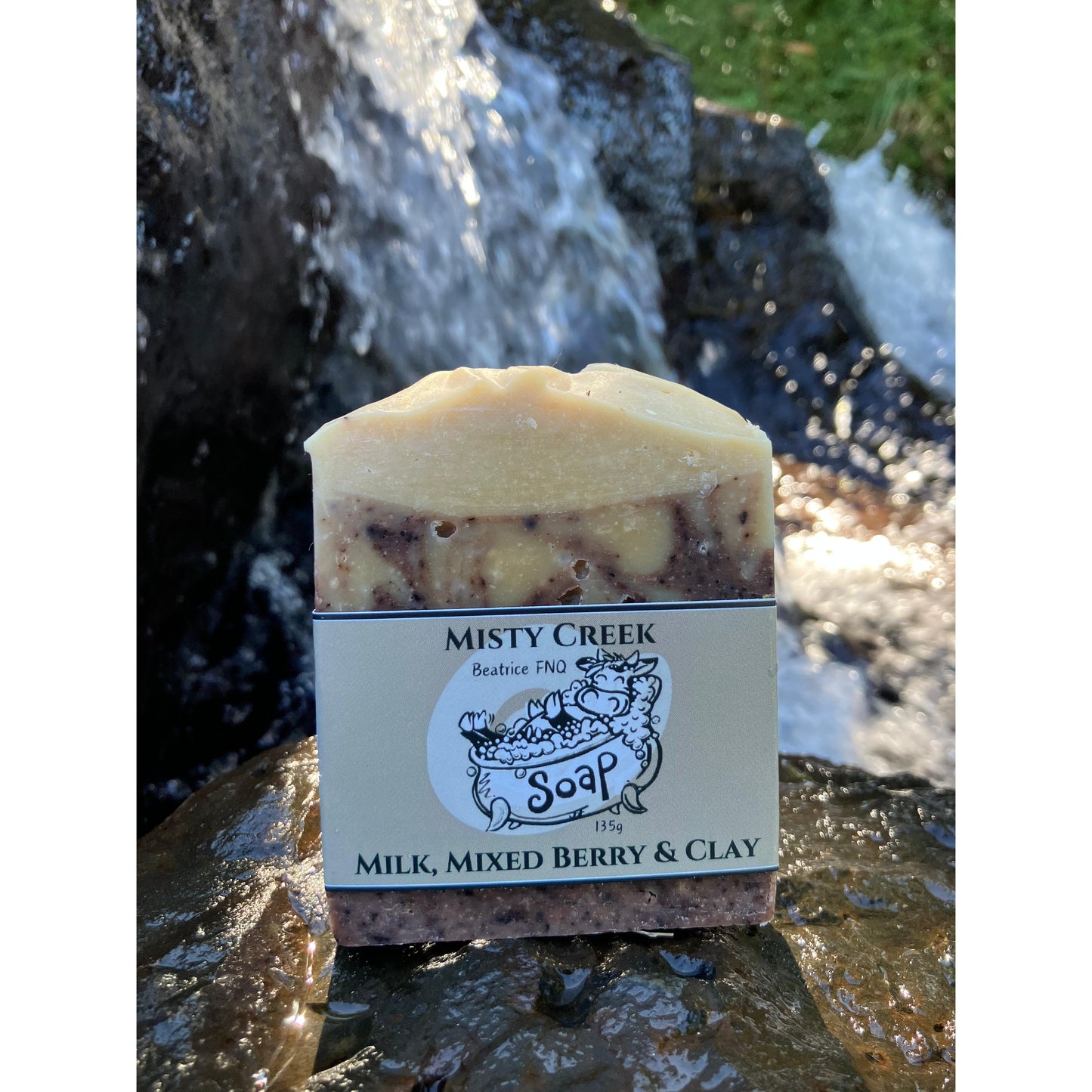 Bar of soap with 'Misty Creek Soap' label on a natural background featuring a waterfall